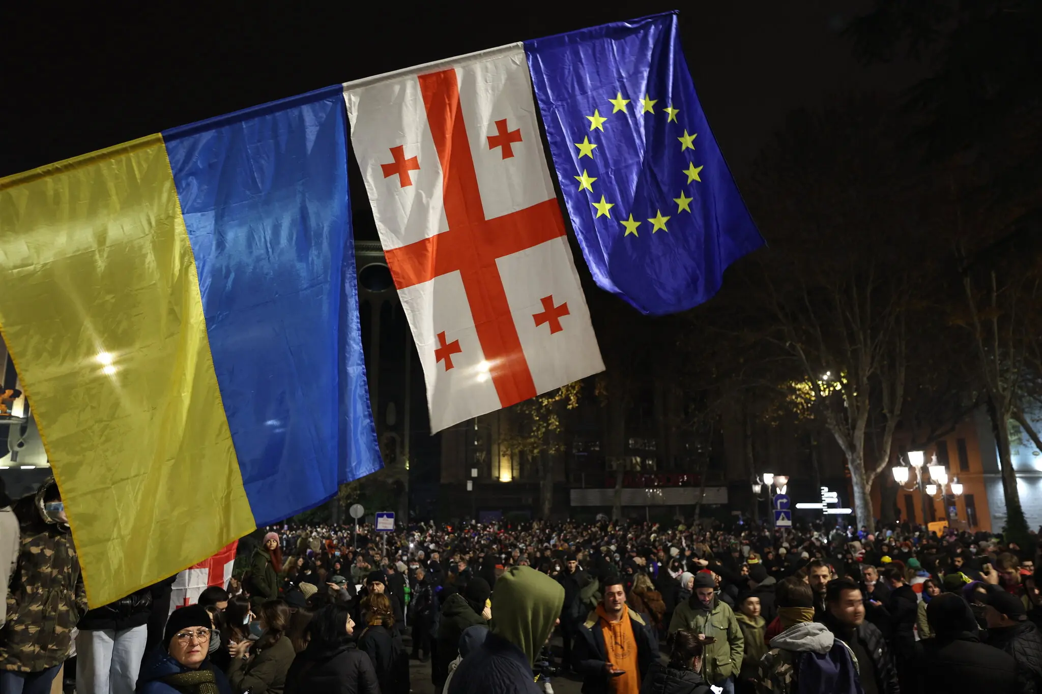 Протестувальник у масці жестикулював перед імпровізованою барикадою.